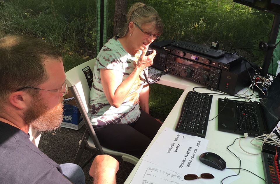 this is a picture of a woman operating an amateur radio with a man observing.